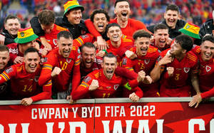 威爾斯足球隊以喜悅的表情和高舉的拳頭慶祝勝利。 — FIFA 世界盃 壁紙