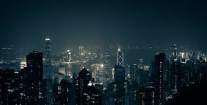 夜間城市景觀，有燈火通明的摩天大樓和黑暗的天空。 — 香港 壁紙