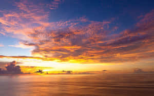 平靜海洋上色彩繽紛的雲彩倒映在水中的鮮豔日落。 — 夕陽天空 壁紙