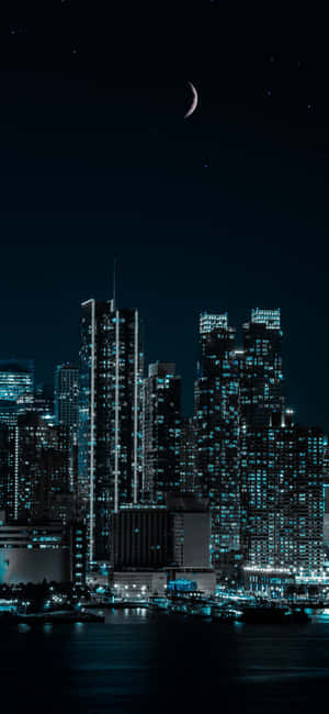 夜景天際線，發光建築物和月亮在水面上 — iPhone 12 mini 壁紙