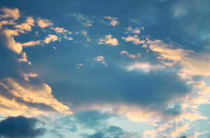柔和藍色和金色雲彩在寧靜的日落天空中發光。 — 藍天 壁紙