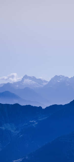 寧靜的藍色山脈，雪覆蓋的山峰和層疊的山脊逐漸消失在霧中。 — 紅色美學 iPhone 壁紙