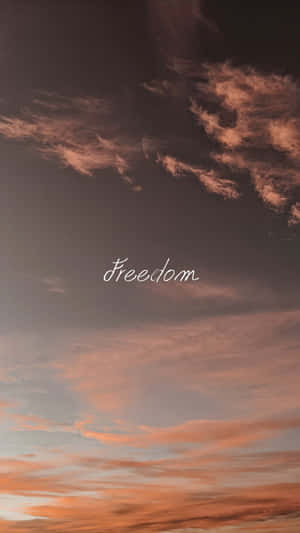 深色天空，橙色粉紅色雲彩，白色字體「自由」 — 自由 壁紙