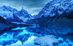 積雪的山峰倒映在平靜的藍色湖面上，在黃昏時分。 — 山脈 壁紙
