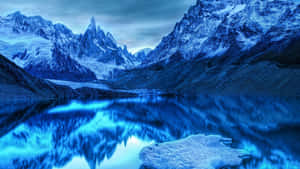 積雪的山峰倒映在暮色中平靜的藍色湖泊裡。 — 雪山 壁紙