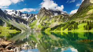 藍天下，高山湖泊映照著雪山和綠丘。 — 湖泊 壁紙