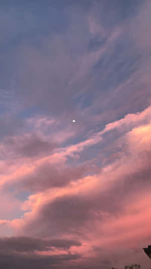 黃昏時的粉紅與紫色雲彩，上方有一輪小月亮 — 暮光 壁紙
