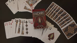 尤克紙牌遊戲在深色桌子上與紅色牌盒一起散開。 — 撲克牌桌 壁紙