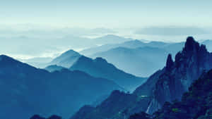 寧靜的山脈，帶有霧氣層次和岩石山峰。 — 山脈 壁紙