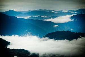 黃昏時分，雲霧在山峰間飄蕩的寧靜山景。 — 美麗的藍色 壁紙