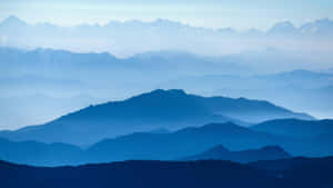 寧靜的山景，層疊的山峰消失在藍色薄霧中。 — 山景 壁紙