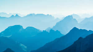 寧靜的山景，層層疊疊的山峰逐漸消失在藍色霧氣中。 — 藍色美學電腦 壁紙