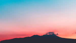 日落時分的山脈剪影，天空呈現粉紅色和藍色 — 夕陽天空 壁紙