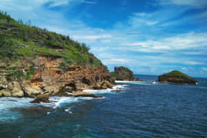 海岸懸崖，海浪拍打，綠色植被，部分多雲的天空。 — 藍色美學電腦 壁紙