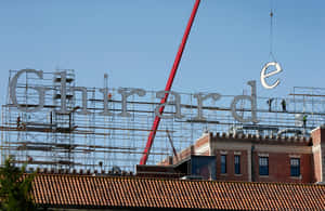 工人用紅色起重機在磚砌建築上安裝一個大型 Ghirardelli 標誌。 — 城市 壁紙