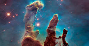 在充滿活力的星雲中的宇宙柱，伴隨著閃爍的星星和深藍色宇宙塵埃。 — NASA 動態圖片 壁紙