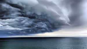 戲劇性的風暴雲懸浮在平靜的海洋地平線上。 — 天氣 壁紙