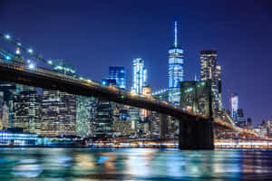夜晚的布魯克林大橋，城市燈光倒映在水面上 — 紐約 壁紙