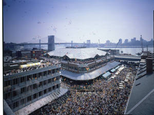 人群在布魯克林海濱市場慶祝，背景有氣球和大橋。 — 復古 壁紙