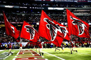 Falcons 足球隊旗幟在夜間比賽中被球員在場上揮舞。 — 慶祝 壁紙