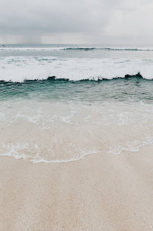 海浪在陰天之下輕輕拍打沙灘。 — 海灘 壁紙