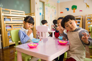 兒童在幼稚園教室的粉紅色桌子上吃零食。