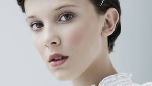 短黑髮和柔和化妝的年輕女性的工作室肖像。 — 米莉·芭比·布朗 壁紙