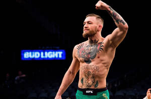 康納·麥格雷戈在UFC比賽中舉起拳頭慶祝勝利，刺青清晰可見。 — 終極格鬥冠軍賽 壁紙