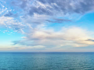 寬闊的海平線，散落的雲朵和遠處的小船。 — 海洋藍 壁紙