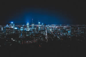 夜晚充滿活力的城市景觀，摩天大樓在黑暗的天空下閃閃發光。 — 城市風景 壁紙