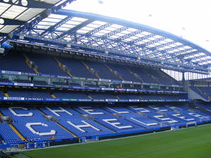 空的藍色體育場座位在綠色球場上以白色字母拼出CHELSEA。 — 切爾西 壁紙