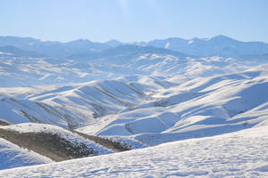 陽光下白雪覆蓋的山景，天空湛藍 — 烏茲別克 壁紙