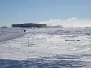 雪地摩托車在雪原上，靠近建築物，天空清澈湛藍 — 冬季風景 壁紙