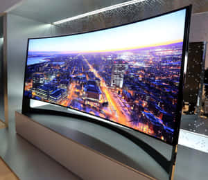 弧形電視顯示暮色中的雪景城市，帶有明亮的燈光 — 電視 壁紙