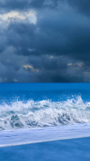暴風雨的海浪在烏雲下翻騰，金色光芒穿透雲層。 — 波浪 壁紙