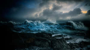 暴風雨的海浪在戲劇性的黃昏天空下衝擊著黑暗的岩石。 — 黑夜 壁紙