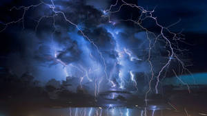 強大的閃電照亮了夜間反射水面上的烏雲。 — 最佳桌面 壁紙