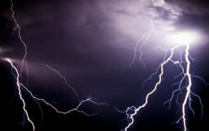 強大的閃電以紫色和白色閃光照亮了黑暗的暴風雨天空。 — 閃電麥坤 壁紙