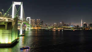 彩虹橋在夜間於東京灣上發光，城市燈光與小船映照在水面。 — 東京鐵塔 壁紙