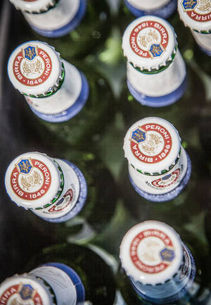 Peroni 啤酒瓶蓋在深色托盤中排列的特寫。 — 麥迪遜·比爾 壁紙