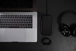 現代科技設置，在深色表面上配有筆記型電腦、電話、耳機和智慧手錶。 — BTS 筆電 壁紙