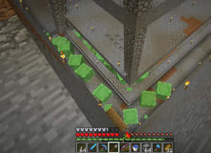 Minecraft玩家在石結構中挖掘綠色方塊，火炬和庫存可見。 — 低調 壁紙