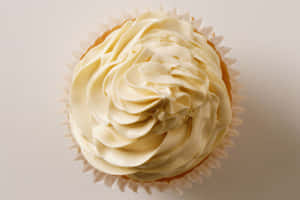 一個放在紙杯裡的杯子蛋糕，上面有奶油白色糖霜。 — MacBook Air M3 壁紙