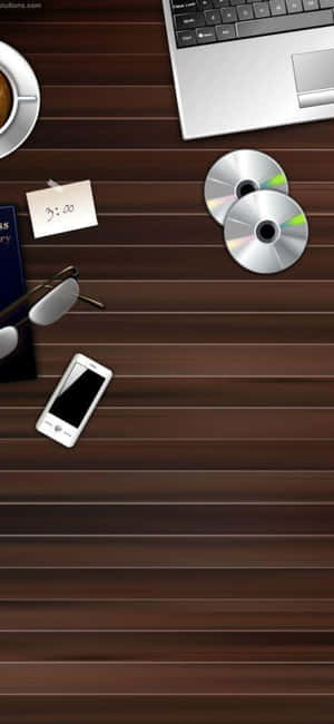 木製書桌，上有筆記型電腦、咖啡杯、眼鏡、電話和CD — iPhone 16 壁紙