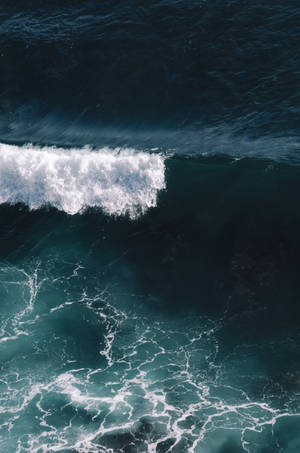 從上方觀看，一道海浪拍打深藍色海水，激起白色泡沫。 — 水 壁紙