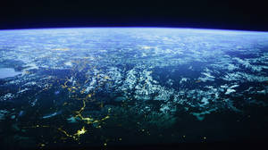 從太空觀看地球的夜景，顯示城市燈光和雲層。 — Pro Display XDR 壁紙