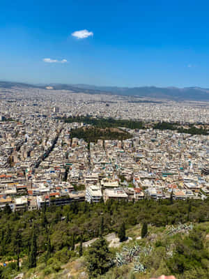 雅典全景，綠色的山丘和遠處的山脈在明亮的藍天下。 — 城市風景 壁紙