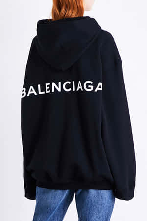 穿著黑色 Balenciaga 連帽上衣和藍色牛仔褲的人，從後方觀看。 — 巴黎世家 壁紙