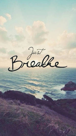 海岸懸崖俯瞰海洋，夕陽和「Just Breathe」文字疊加。 — 呼吸 壁紙