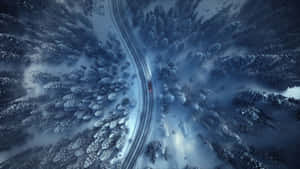 從上方看，一輛紅色汽車在冬季森林的雪路上行駛。 — 冬季風景 壁紙
